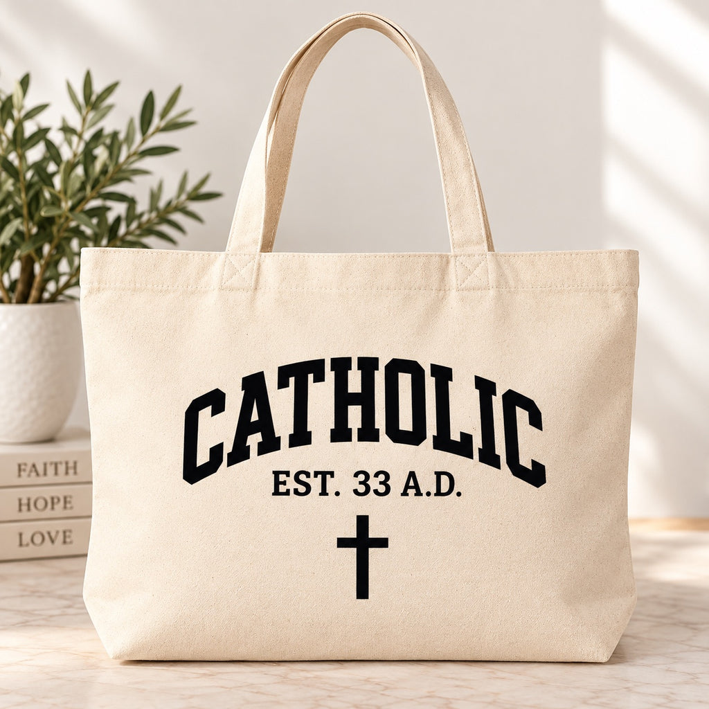 Cream tote bag with black Catholic lettering, EST. 33 A.D. text, and a cross.
