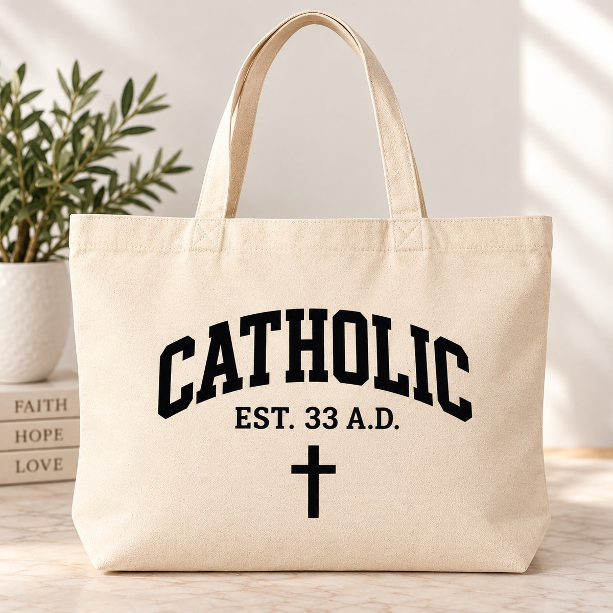 Cream tote bag with black Catholic lettering, EST. 33 A.D. text, and a cross.