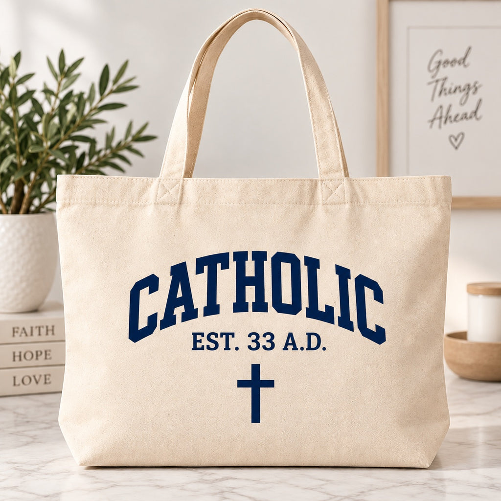Cream tote bag with dark blue Catholic lettering, EST. 33 A.D. text, and a cross.