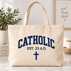Cream tote bag with dark blue Catholic lettering, EST. 33 A.D. text, and a cross.