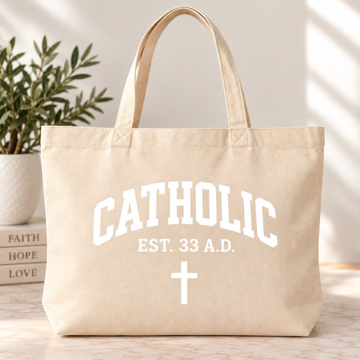 Cream tote bag with white Catholic lettering, EST. 33 A.D. text, and a cross.