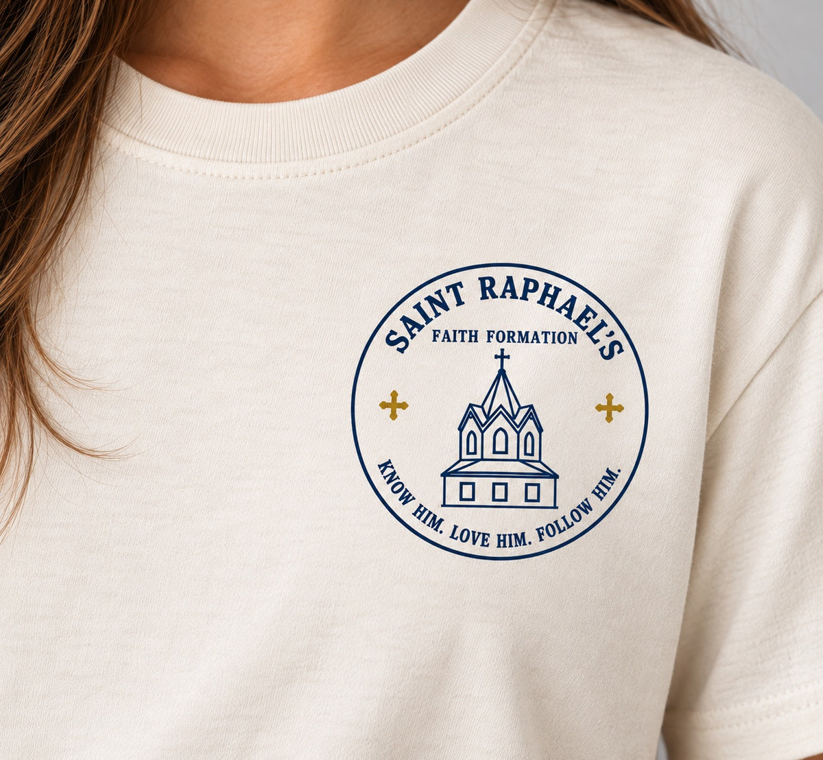 Close-up of the Saint Raphael’s Faith Formation design on the cream T-shirt