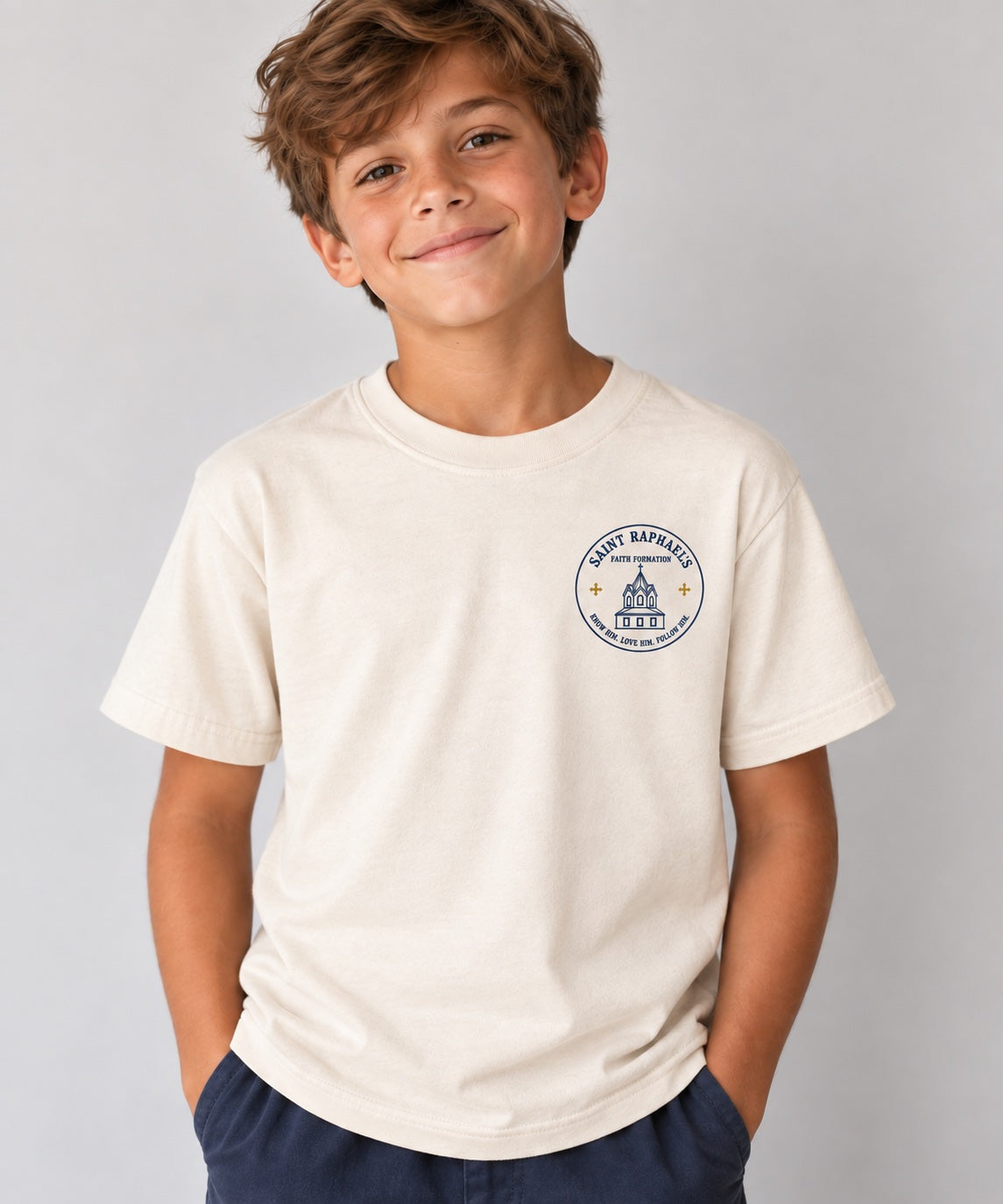 Saint Raphael’s Faith Formation youth T-shirt in cream, worn by a boy