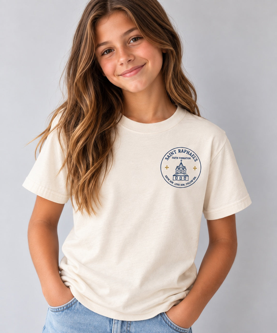 Saint Raphael’s Faith Formation youth T-shirt in cream, worn by a girl