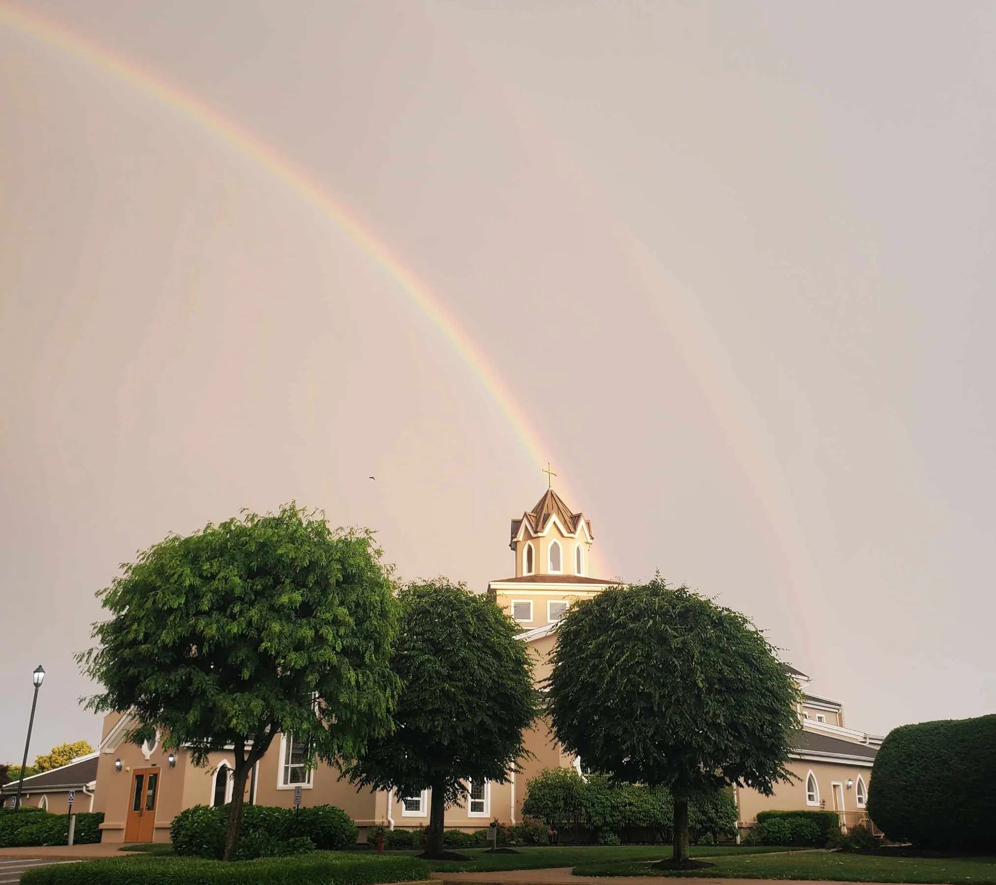A rainbow above the cross and bell tower of St. Raphael Church in East Meadow
